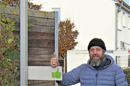 Derek Palme am Klappschild mit dem grünen Daumen.
