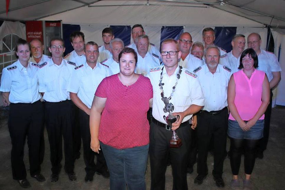 König Frank Paustian (mit Königskette und Pokal) mit Ehefrau Nicole Paustian bei der Königsproklamation vor den Kameraden der Feuerwehr Lensahnerhof.