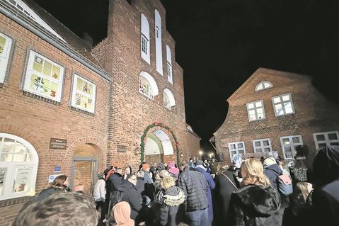 Viele Gäste verfolgen die feierliche Öffnung der ersten Adventsfenster am historischen Kremper Tor.