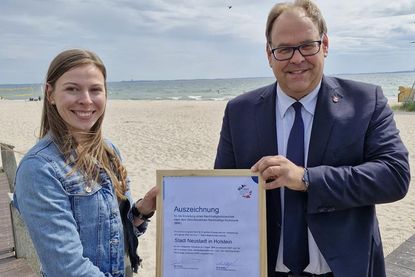 Bürgermeister Mirko Spieckermann und Nachhaltigkeitsmanagerin Lina Sophie Koop mit der Auszeichnung für die erfolgreiche Projektteilnahme „BNK bundesweit 2024“, in dessen Rahmen die Berichtserstellung nach dem Berichtsnahmen Nachhaltige Kommune (BNK) erfolgte. (Foto: Stadt Neustadt in Holstein)