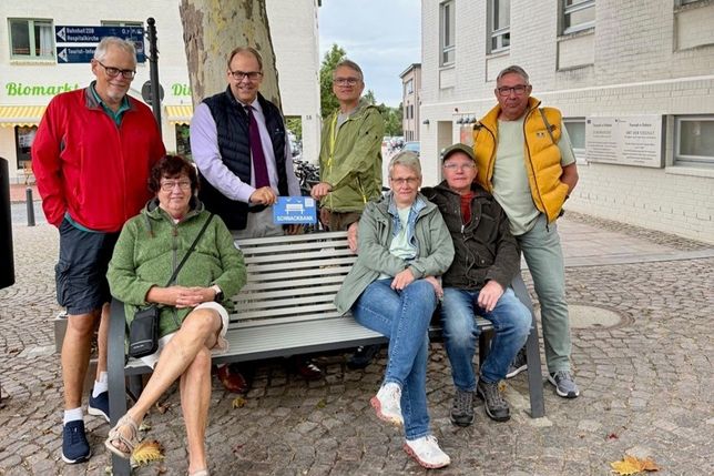 Bürgermeister Mirko Spieckermann (3. v. lks.) und Projektvertreter Björn Streich (4. v. re.) brachten die Schnackbank-Plakette gemeinsam mit einer Urlaubergruppe aus Nordrhein-Westfalen an.