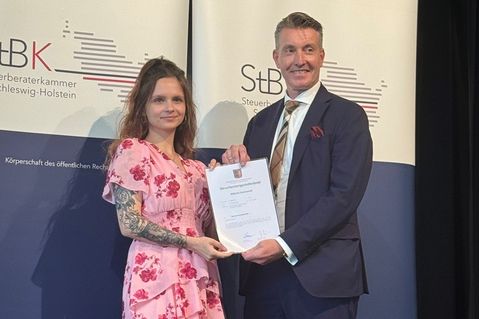 Wiktoria Stasinowski nimmt ihren Steuerfachangestelltenbrief entgegen.