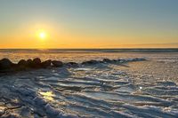 Eis, Meer und Abendsonne: Die Sonne spiegelt sich im gefrorenen Uferbereich und taucht die Ostseeküste in warmes Gold.