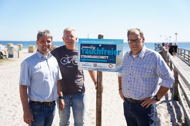 Links von der Seebrücke soll in Zukunft auf einem Abschnitt von circa 150 Metern nicht mehr geraucht werden, auf freiwilliger Basis. Stephan Reil vom Tourismus-Service, Ortsbeiratsvorsitzender Lars Prigge und Bürgermeister Mirko Spieckermann (v. lks.) präsentierten die neu aufgestellten Schilder.