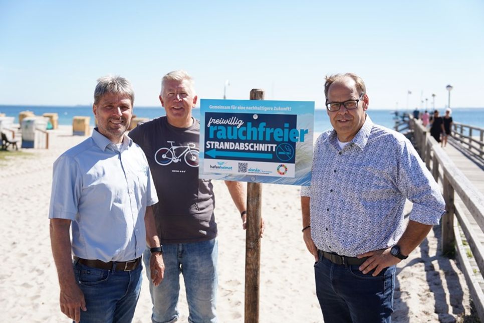 Links von der Seebrücke soll in Zukunft auf einem Abschnitt von circa 150 Metern nicht mehr geraucht werden, auf freiwilliger Basis. Stephan Reil vom Tourismus-Service, Ortsbeiratsvorsitzender Lars Prigge und Bürgermeister Mirko Spieckermann (v. lks.) präsentierten die neu aufgestellten Schilder.