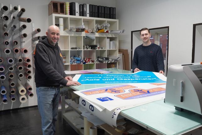 Firmengründer Axel Hohmuth (lks.) und sein neuer Geschäftspartner Mattis Körting präsentieren frisch produzierte Plakate in den Räumen in der Hochtorstraße.