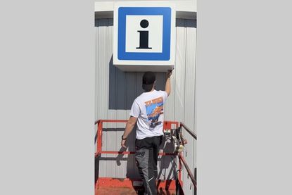 Von der Arbeitsbühne aus wird eine neue Lichtwerbeanlage montiert und millimetergenau an der Fassade angebracht.