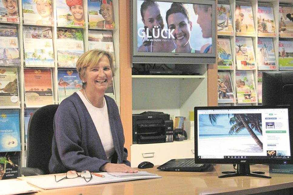 So kennt man Katarina Clarus: fröhlich hinter ihrem Schreibtisch sitzend im „ESKA-Reisebüro“ zwischen Urlaubskatalogen und Computerbildschirmen.