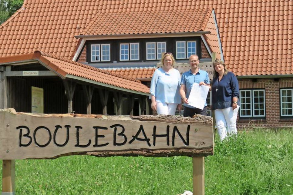 Dana Ahrens, Jörg Bouman und Iris Görtz (v. lks.), im Hintergrund die alte Jugendherberge mit der Boulebahn.