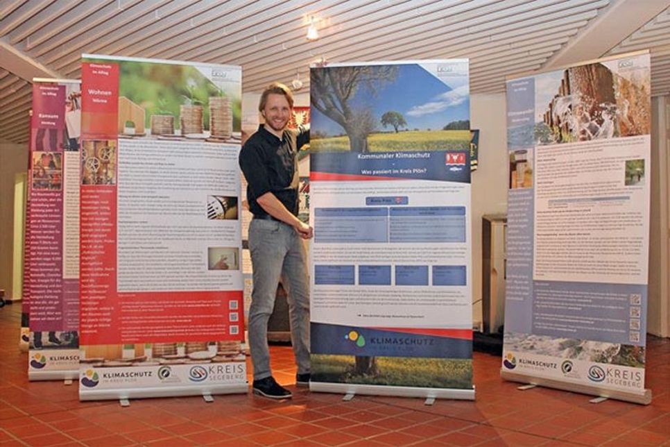 „Der Klimaschutzmanager des Kreises Plön, Dr. David-Willem Poggemann, baut die mobile Klimaschutz-Ausstellung im Foyer des Kreishauses auf und freut sich auf interessierte Besucherinnen und Besucher.“