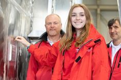Unter den Augen ihres Vaters und Seenotretter Markus Davids (l.) sowie Vormann Guido Förster hält Merle Davids die Bremer Zwei-Euro-Münze für die Fotografen schon einmal an die richtige Stelle, bevor sie sie endgültig in die Aluminiumtasche fallen lässt.