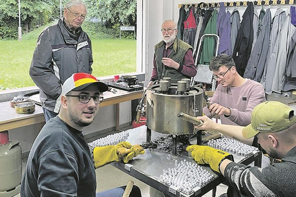 Die Schützenbrüder Gerrit Proch, Lauritz Godow und ein Gilde-Interessent beim Gießen ihrer Bleikugeln für die Vorderlader-Gewehre. Senioren Alfred und Peter im Hintergrund führen Aufsicht (v.li.)