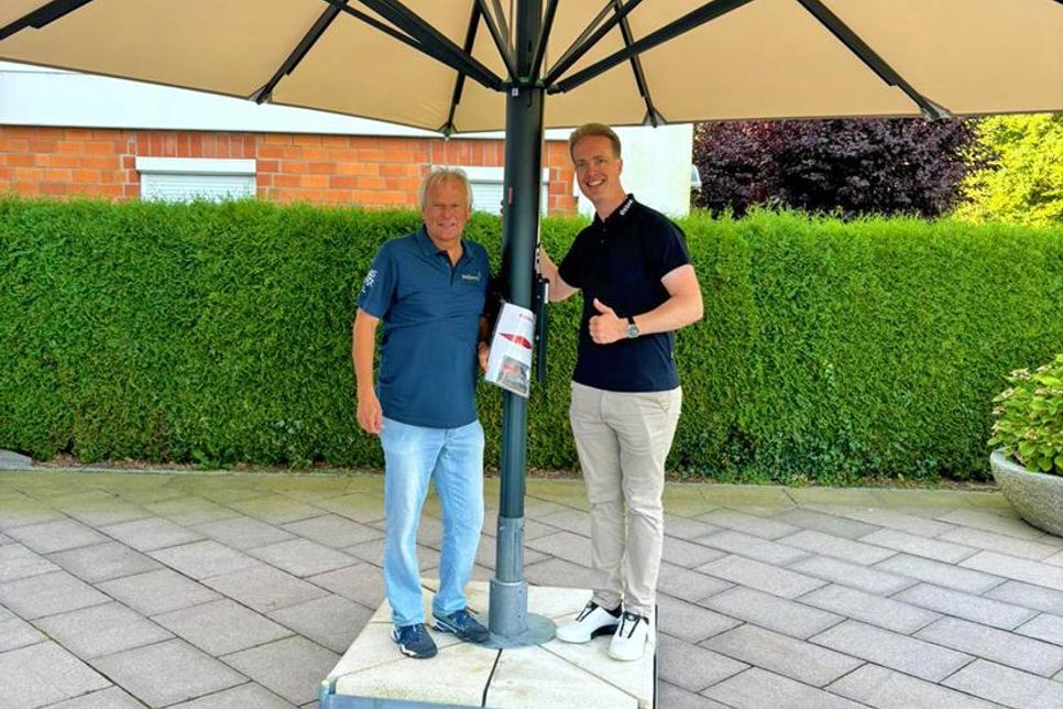 Dirk Weber-Klüver (lks.) und Hauke Otten präsentieren den Sonnenschirm für den Kindergarten.