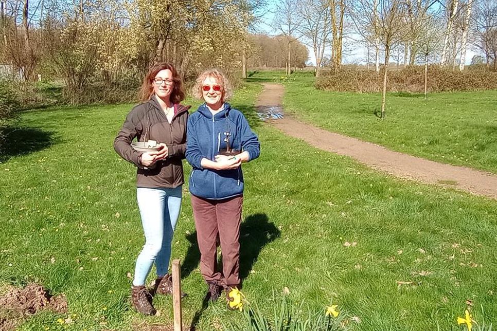 Bürgermeisterin Stefanie Friedrich-Suhr und Meike Kirbis (v. lks.) mit zwei Walnuss-Setzlingen.