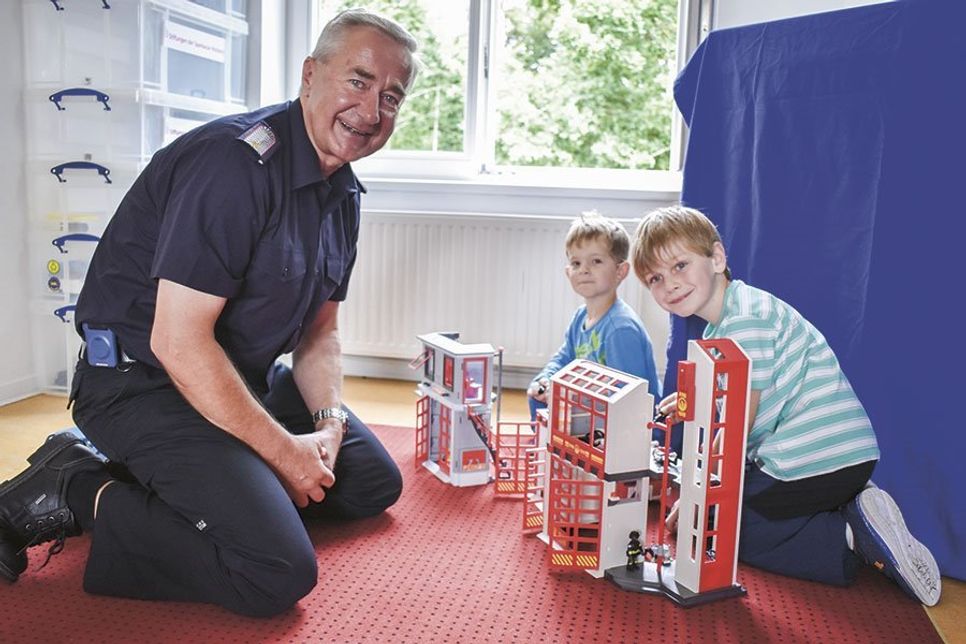 Bosse (vorne) und Deik spielen vor den Augen von Knut Hansen, stv. Wehrführer der Freiwilligen Feuerwehr Pansdorf, mit der Feuerwehrstation von playmobil.