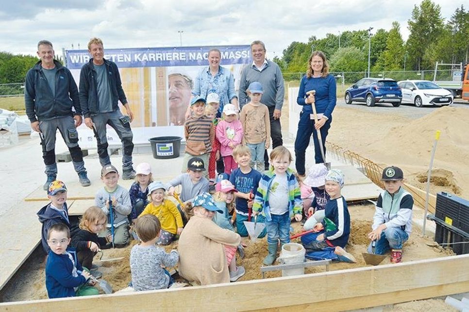 Vor den Augen von Katrin Engeln (v.r.), Bürgermeisterin der Stadt Bad Schwartau, Architekt Uwe Witaszak, Lebenshilfe Vorstand Jessica Groß und Mitarbeitern der bauausführenden Firma Gollan buddeln die Kinder aus der Kita am Papenmoor ein Loch und versenken die „Zeitkapsel“.