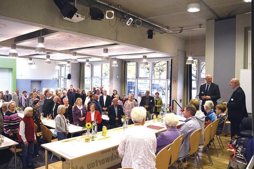 Klaus Nentwig (mit Mikrofon neben Wolfgang Dunker) bat die Gäste, sich zu Ehren der AWO- und der Tafel-Ehrenamtler zu erheben und sie mit einem Lied hochleben zu lassen.