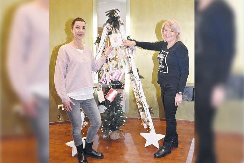 Friseurmeisterin Bettina Wiese (links, neu im Team vom „Frisurenland“) und Inhaberin Sylvia Land-Inselmann vor dem Wunschbaum im Scharbeutzer Fiseursalon.