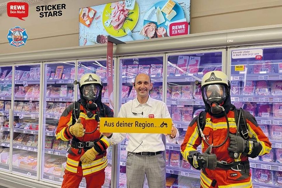 Die Freiwillige Feuerwehr Scharbeutz und die REWE-Marktleitung freuen sich über den Verkaufsstart der Stickeralbum-Aktion zu Gunsten der Feuerwehr.