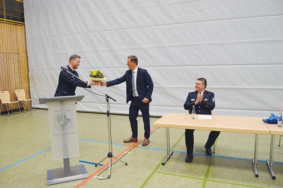 Mit gebührendem Abstand gratuliert Ratekaus Bürgermeister Thomas Keller (m.) vor den Augen von Kreisbrandmeister Thorsten Plath dem frisch gewählten Gemeindewehrführer Christian Ziemann und überreicht einen Blumenstrauß.