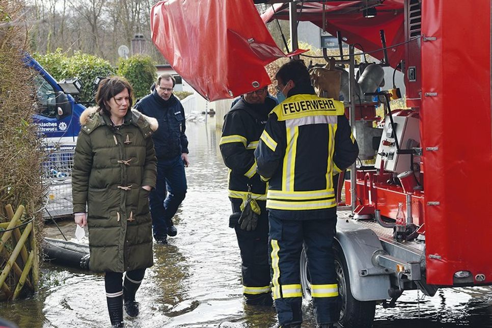 Innenstaatssekretärin Kristina Herbst macht sich in Gummistiefeln unter anderem im Erlenweg in der Aalbeek-Siedlung ein Bild von dem dortigen Hochwasser. Begleitet wird sie von Vertretern der Gemeinde, THW und Feuerwehr.