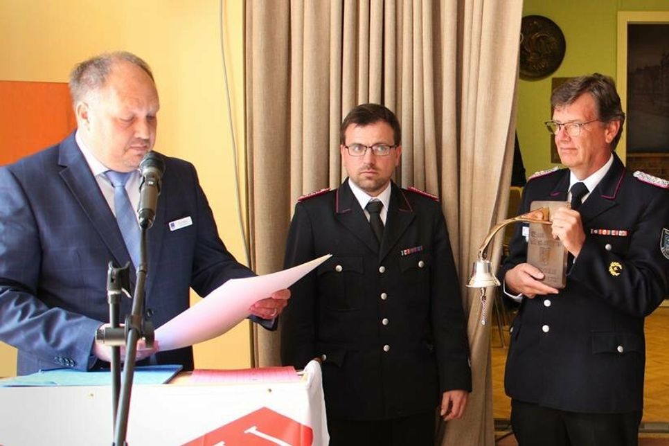 Der stellvertretende Landrat Timo Gaarz (lks.) und Kreiswehrführer Michael Hasselmann (2. v. re.) übergaben die Silberne Glocke des Landes Schleswig-Holstein an Gemeindewehrführer Tobias Kutrieb.