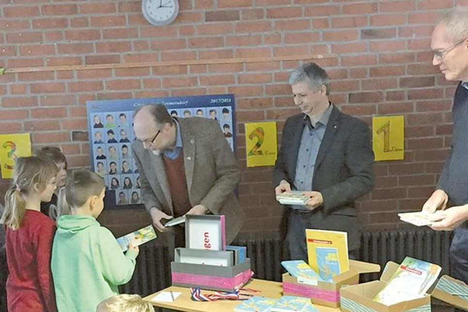 Rotarier Horst Simonsen, Frank Conrad und Hubertus Meyer verteilen Bücher an die Schüler der Grundschule Gremersdorf.