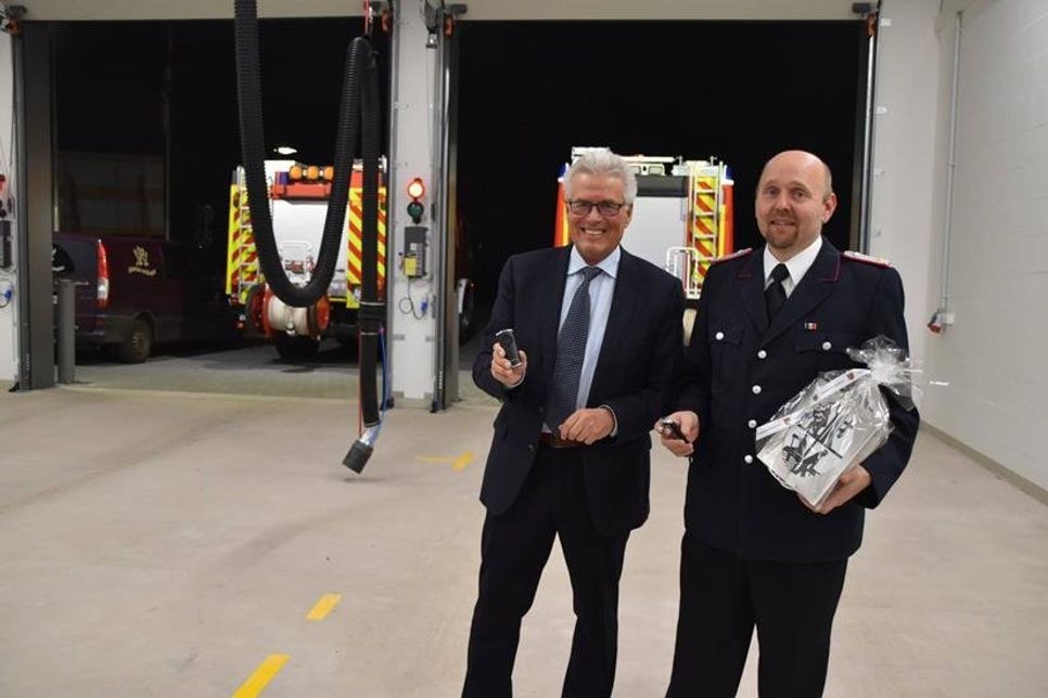 Mit Knopfdruck auf die Fernbedienungen öffnen sich die Rolltore im neuen Anbau des Feuerwehrgerätehauses: Ortswehrführer Sven Reimers und Bürgermeister Volker Owerien probieren es zur offiziellen Einweihung aus. (Fotos: René Kleinschmidt)