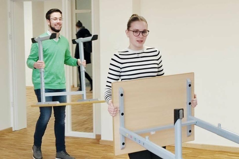 Die Oberstufenschüler helfen beim Einräumen von Stühlen und Tischen in ihren zukünftigen Klassenzimmern.