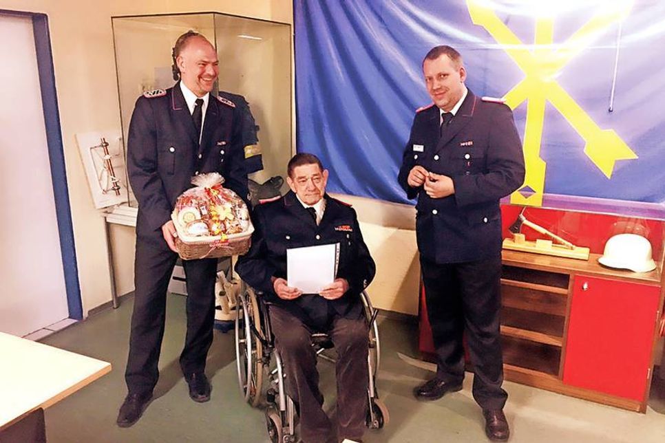 Gruppenführer Claus Meinke (l.) und Wehrführer Dennis Wichelmann (r.) gratulieren Manfred Stuhr (Mitte) mit einem Präsentkorb zur besonderen Ehrung für 60 Jahre Mitgliedschaft in der Freiwilligen Feuerwehr.