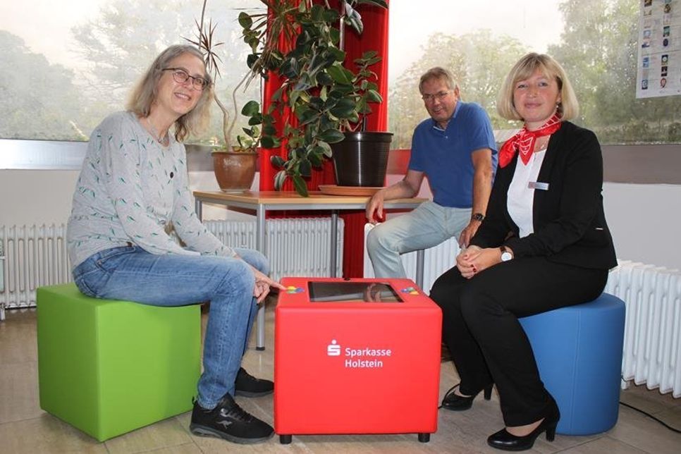 Sie freuen sich gemeinsam über die Unterstützung der Sparkasse Holstein bei der Anschaffung des KuTi-Würfels für die  Gemeindebücherei in Lensahn: Sparkassen-Filialleiterin Janina Oldekop-Timm (re.), Büchereileiterin Turit Flohr und Bürgermeister Klaus Winter.