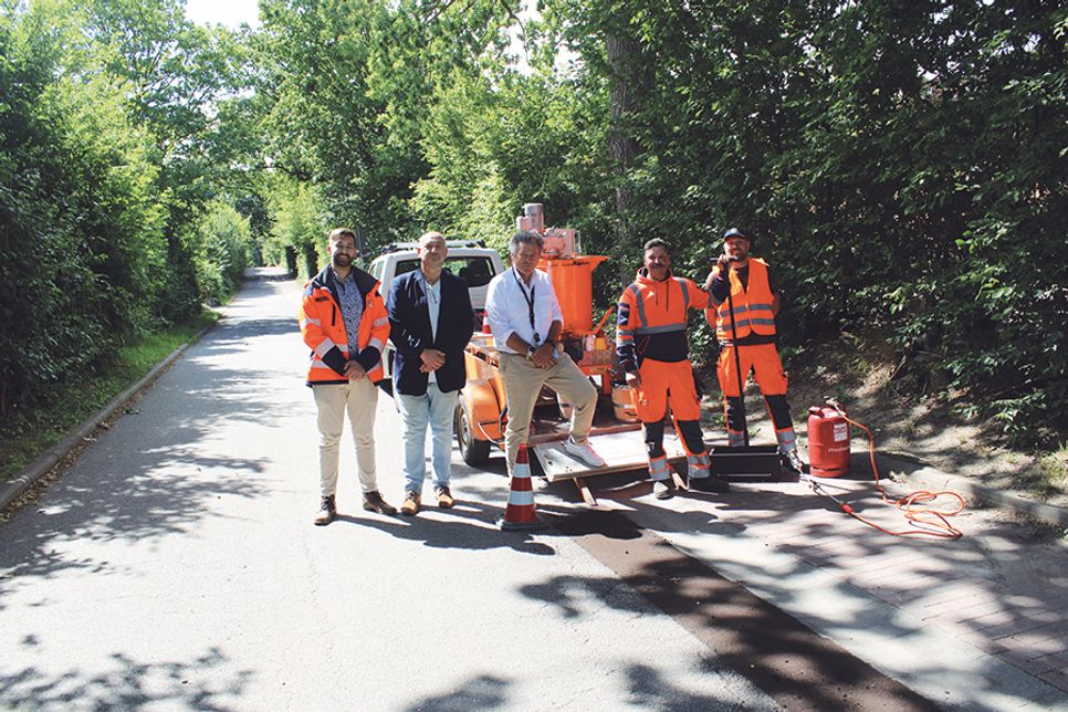 Im verkehrsschwachen Grünen Redder fand die Präsentation des Straßenvergussaufbereitungskochers statt (v.li.): Bauhofsleiter Fabian Jungenkrüger, Peter Mowka (Geschäftsbereichsleiter Planung und Bauservice), Bürgermeister Andreas Zimmermann sowie die Bauhofsmitarbeiter Torsten Senf und Jakob Kolbe.