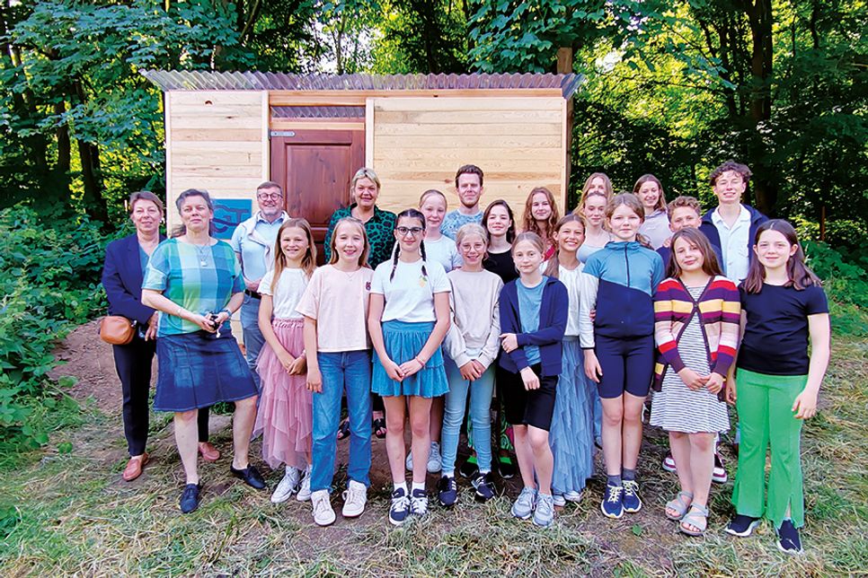 Die Schülerinnen und Schüler der Garten-AG freuen sich mit ihrem Lehrer Philipp Pern (Mitte), Hoteldirektorin Manja Brandt (links), Schulleiterin Dr. Cordula Braun, Bürgermeister Sven Partheil Böhnke und Gesine Muus, Werkleiterin des Kurbetriebes, über ihr neues Gartenhaus, das Dank der Spende erbaut werden konnte.