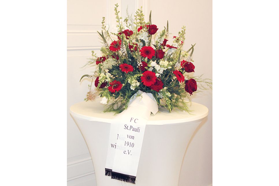 Der übergebene Blumenkranz mit dem Vereinsnamen und der schemenhaft zu erkennenden Inschrift „Nie wieder“.