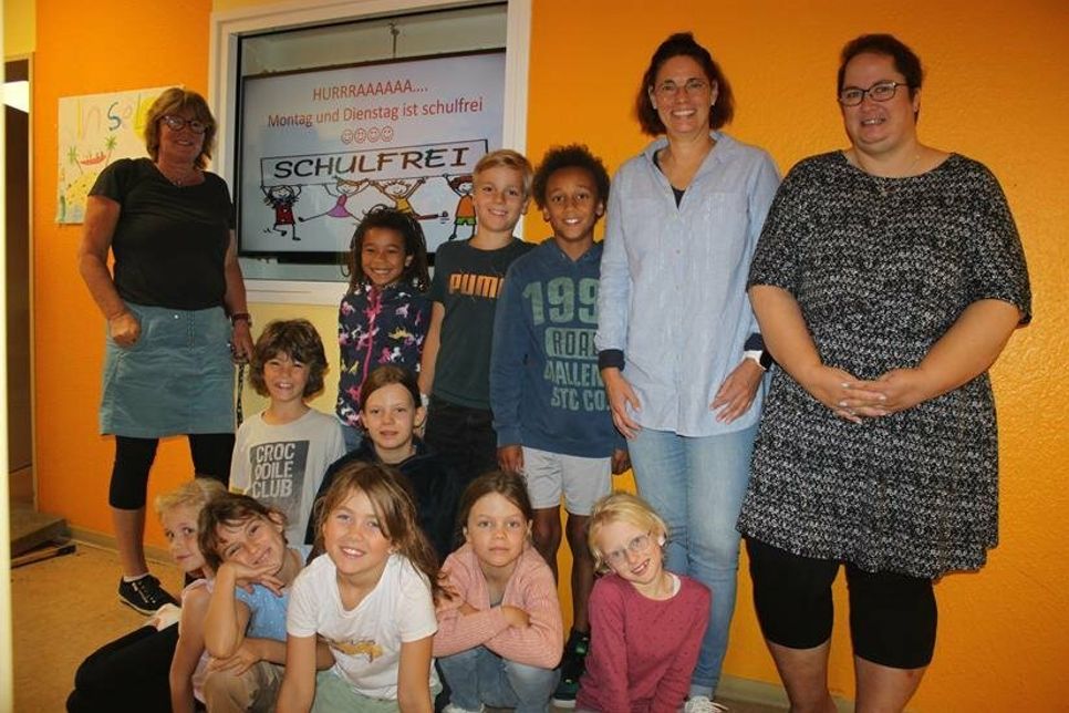 Insel-Leiterin Christel Albrecht (lks.), Schulleiterin Angela Haar (2. v. re.) und Vorsitzende des Fördervereins Nicole Paustian (re.) mit einigen Kindern der „Insel“ vor dem digitalen Info-Bildschirm.
