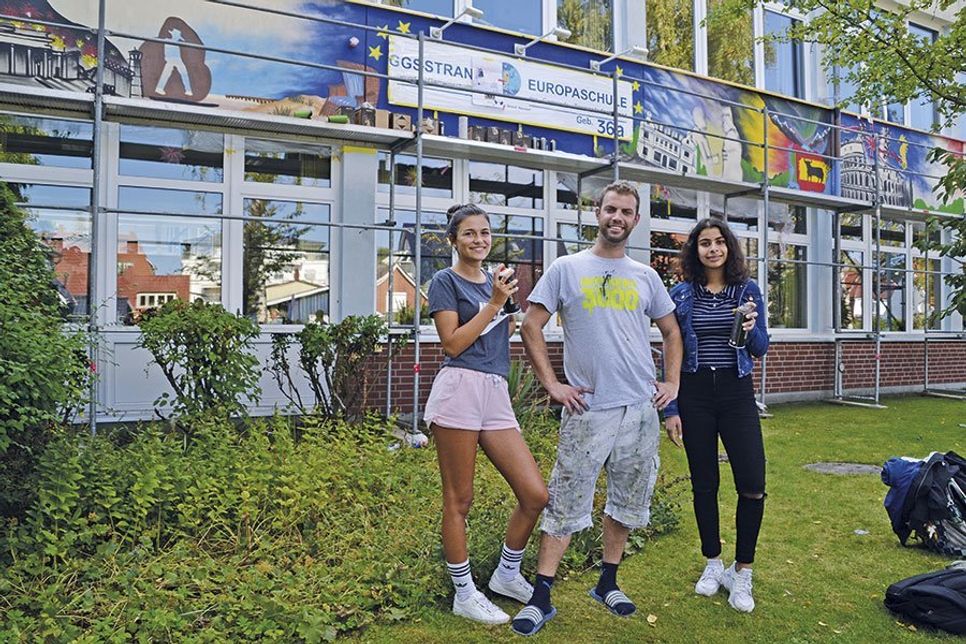Die Schülersprecherinnen Yasemin Tuna und Duygu Can (Klasse 10 b) mit Urban Artist und Street Art-Künstler Henning Marten Feil vor dem Wandgemälde zum Thema „Europa“. (Foto: René Kleinschmidt)