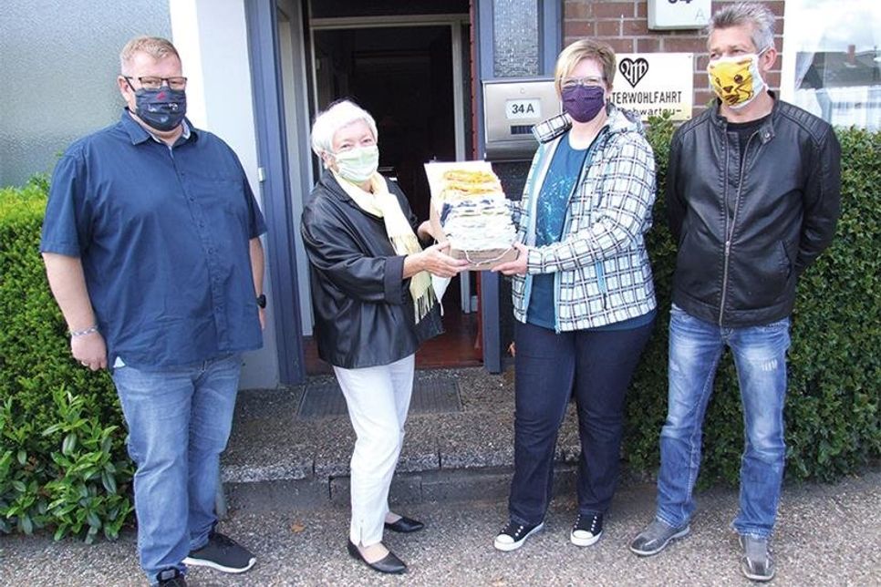Frank Meier (l) und die Eheleute Anja und Dirk Janack übergeben die selbstgenähten Masken an Lioba Mitter (2.v.l.).