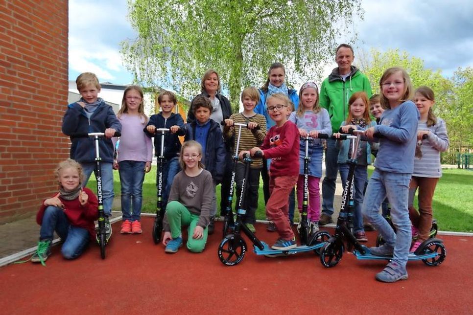 Schulleiterin Michaela Grave, die 1. Vorsitzende des Fördervereins, Frau Casper, der Schulsportobmann der Grundschule, Sönke Holst (hinten v. lks.) sowie stellvertretend einige Schüler der Klasse 1e, die die Roller begeistert in Empfang nahmen.