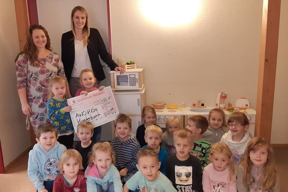 Sie freuen sich gemeinsam über die Hilfe bei der Anschaffung einer neuen Spielzeugküche für den AWO-Kindergarten Kunterbunt in Lensahn: Jasmin Path, Leiterin der Filiale der Sparkasse Holstein (hinten re.) und Erzieherin Daniela Marquardt mit einigen Jungköchen. (Foto: Sparkasse Holstein)