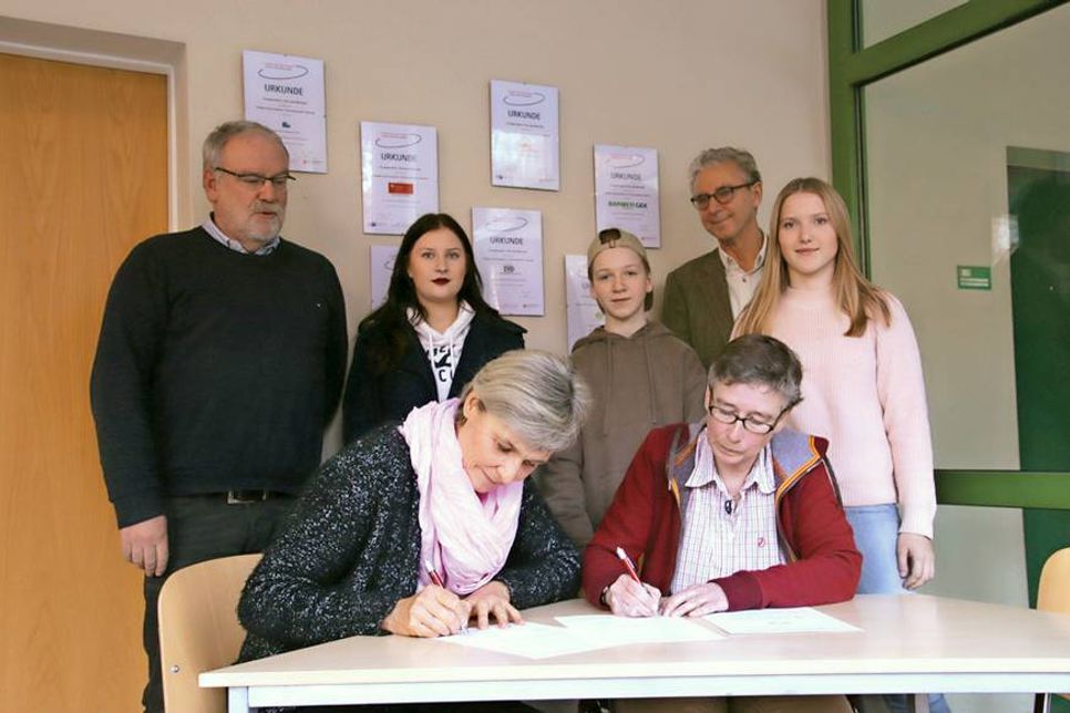 Unterzeichnung des Kooperationsvertrages: Sabine Ebbert (Studien- und Berufsberaterin, Agentur für Arbeit Lübeck) und Meike Niehaus (Koordinatorin für Berufs- und Studienorientierung am OGT) am Tisch mit Oberstufenleiter Volkmar Jaecks (stehend von links), Larissa Klünder (Abiturjahrgang Q2 und Mitglied der Schülervertretung), Schüler Johann Schulz, Schulleiter Michael Bartolf und Lara Kayser (Abiturjahrgang Q2).