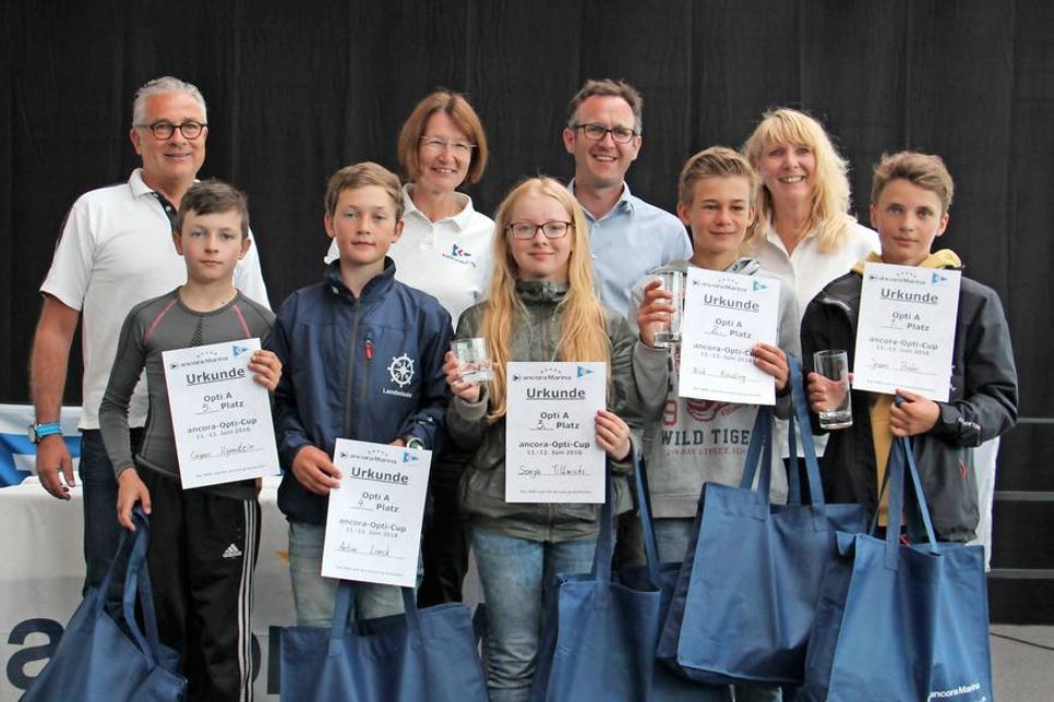 ancora Marina Geschäftsführer Oliver Seiter, Antje Weise (Schiedsgericht),  Wettfahrtleiter Philip Ismar vom NSV und Elke Dippel von der ancora Marina (hi. v. lks.) mit den Gewinnern der Klasse Opti-A.
