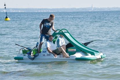 Fabian Harloff (mit Kescher) und Marcus Bade im Tretboot beim Müll aus der Ostsee fischen.
