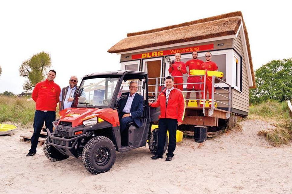 Zufriedene Gesichter bei der Einweihung der neuen DLRG-Wachstation am Scharbeutzer Strand (von links nach rechts): Christoph Niemann und Uwe Justen vom Vorstand des DLRG-Ortsvereins, Bürgermeister Volker Owerien (im Elektro-Beach-Buggy) und der DLRG-Landesgeschäftsführer Thies Wolfhagen sowie die Rettungsschwimmer Lisa Nakaten, Lukas Nuding und Fabian Rinke im Hintergrund. (Foto: René Kleinschmidt)