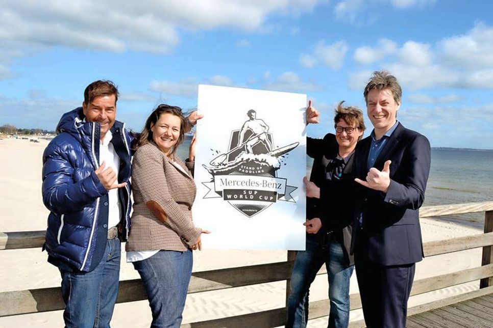 Matthias Neumann (links) und Birgit Ballhause (Act Agency) freuen sich mit Hansjörg Conzelmann und André Rosinski von der Tourismus-Agentur Lübecker Bucht auf den „Mercedes Benz SUP World Cup“ in Scharbeutz.
