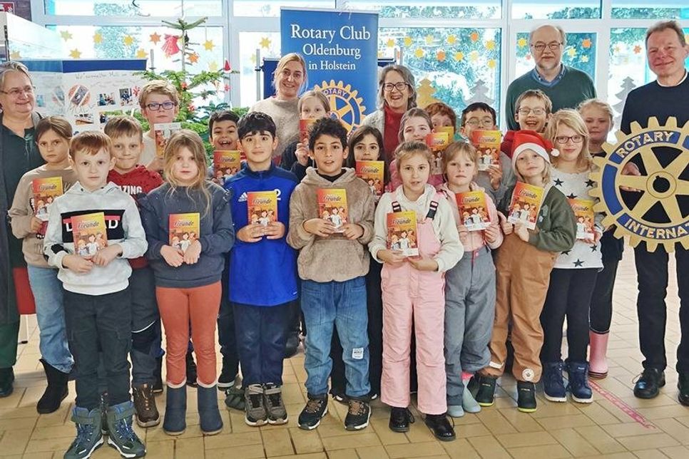 Schüler der Klasse 2 b präsentieren ihre neuen Bücher; im Hintergrund (v.l.n.r): Schulleiterin Gesine Böllnitz, Klassenlehrerin Frau Kirsten Looks, Projektleiterin Susanne Knees und die Rotarier Dr. Horst Simonsen und Dr. Dieter Fischer