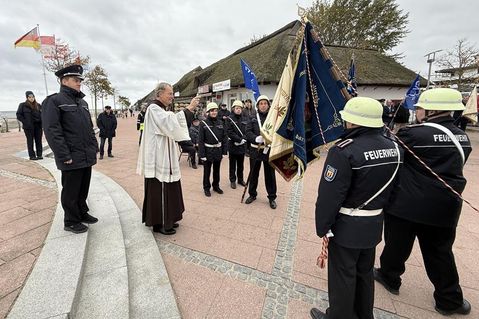 Pater Ralf Winterberg segnet auf dem Nystedplatz in Dahme die neue Fahne der Freiwilligen Feuerwehr.