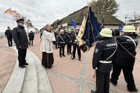 Pater Ralf Winterberg segnet auf dem Nystedplatz in Dahme die neue Fahne der Freiwilligen Feuerwehr.
