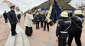 Pater Ralf Winterberg segnet auf dem Nystedplatz in Dahme die neue Fahne der Freiwilligen Feuerwehr.