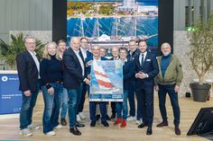 Die Organisatoren der Travemünder Woche stellen das frische Plakat zur TW 2025 vor: Lutz Kleinfeldt (von links), Anja Kamrath, Lorenz Buchler, Frank Schärffe, Jan Lindenau, Petros Michelidakis, Sascha Osterwalder, Andreas Christiansen, Frauke Klatt, Jens Kath, Marius Berlemann und Ralf Schulte.