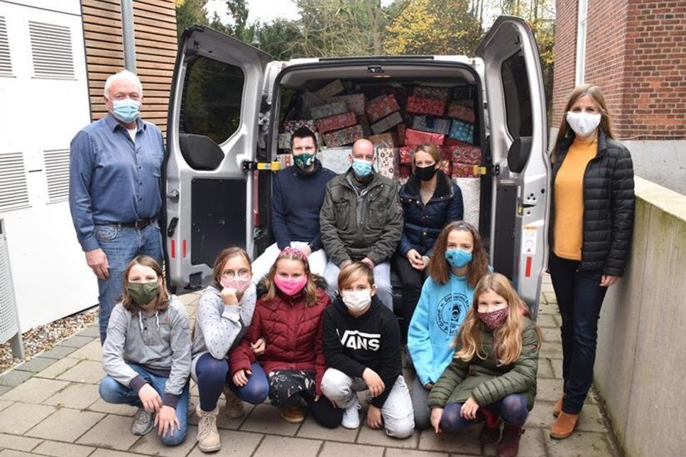 Der Transporter ist mit über 310 Weihnachtspaketen beladen: Schulleiter Peter Schultalbers (li.), Lehrerin Catharina Rieck (re.) und Schüler der Klasse 5c freuen sich mit Patryk Pikura vom Round Table 104 (2.v.li.) und Christian Kumbernuß und Lina Kleinfeldt, die ihn unterstützen, über die erfolgreiche Aktion.